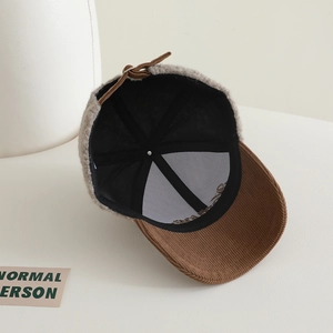 Détail de la casquette en peluche grise avec visière en velours côtelé marron
