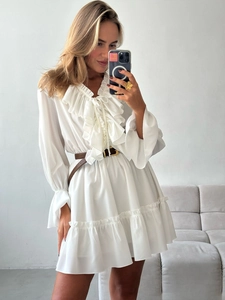 Detail of white V-neck dress featuring layered ruffles and a brown leather belt