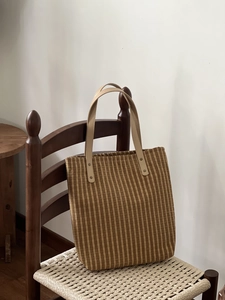 Detail of vintage plaid tote bag featuring brown cotton stripes and leather handles