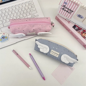 Detail of pink and blue star pattern pencil cases with plush angel wings on a desk