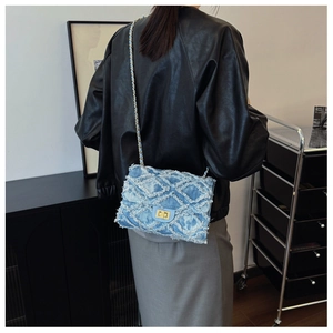 Detail of blue denim crossbody bag featuring quilted patterns and gold lock closure