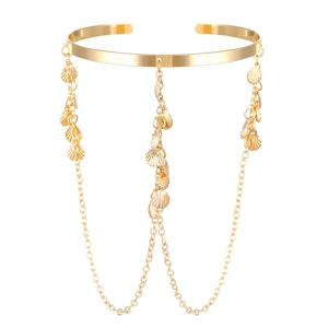 Detail of golden arm cuff with hanging chains and delicate seashell charms on white background