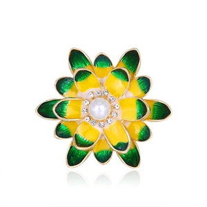 Dettaglio macro di una spilla a fiore gialla e verde con perla centrale e cristalli