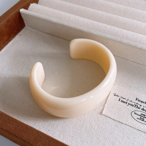 Close-up of cream resin chunky open bangle in a wooden jewelry box with velvet lining