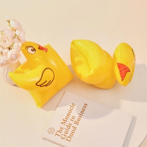 Close-up of yellow cartoon duck inflatable armbands on a desk with lifestyle props