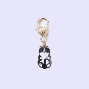 Detailed view of a black and white cat charm with pink paws and a golden heart clasp