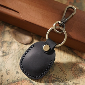 Retro black leather AirTag case with metal keychain set on a vintage map background