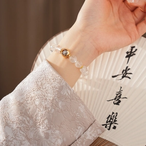 Detailed shot of white crystal beaded bracelet with gold hollow ornament and calligraphy fan