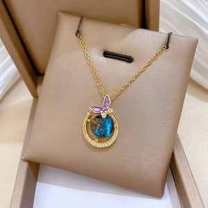 Macro detail of gold necklace with starry crescent moon and purple crystal butterfly