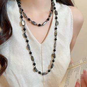 Detail of bohemian long beaded necklace with iridescent shell slices and gray crystal beads
