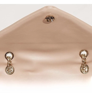 Detail view of gold magnetic snap closure and chain on beige V-quilted faux leather bag