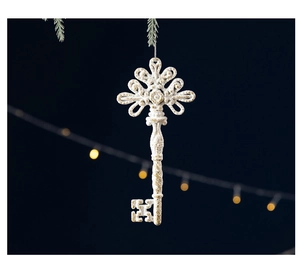 Detail of white and gold star Christmas ornament hanging on a pine branch with bokeh lights