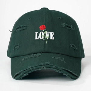 Close-up of rose embroidery and LOVE text on distressed dark green baseball cap