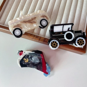 Detail showing vintage racing car and black classic car acetate hair claws on velvet tray