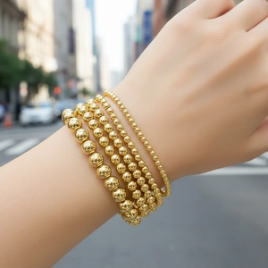 Close-up of five-piece 18K gold plated beaded stretch bracelets stacked on a wrist