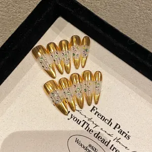 Golden handmade press-on nails with luxury rhinestones and fine vertical line details