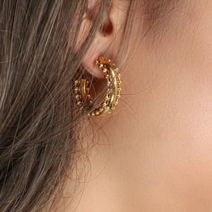 Close-up of three-tier gold-plated hoop earrings with bead texture on model ear