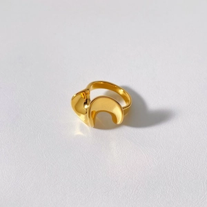 Macro shot of gold plated stainless steel irregular wavy ring on textured white background