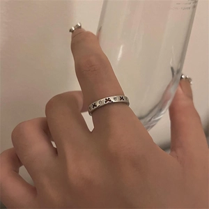 Detail showing 925 silver ring with engraved cross pattern and small stones worn on finger