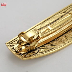 Close-up of vintage gold metal hair clip showing intricate leaf patterns and spring clasp