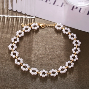 Detail of floral pearl choker with gold chain and lobster clasp on textured surface