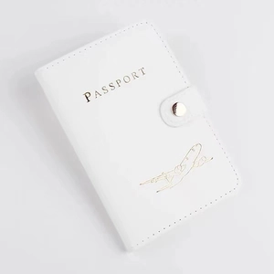 Detailed macro view of white PU leather passport cover with gold airplane stamp and button