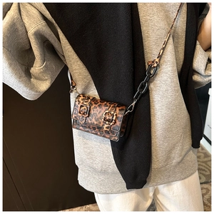 Detail of leopard print mini crossbody bag with black acrylic chain and belt buckles