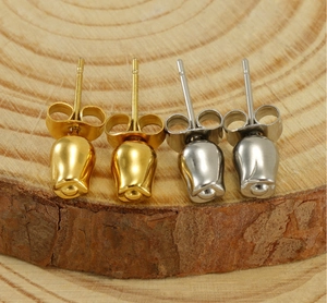 Detailed view of gold and silver rose bud stud earrings on a wooden background
