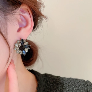 Close-up of flower stud earring with black and clear crystals on a model's ear