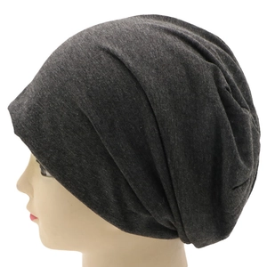Detail of the side profile and knitted texture of a dark grey slouchy beanie hat