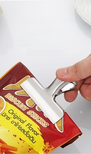 Macro detail of large stainless steel T-shape food clip sealing a snack bag tightly