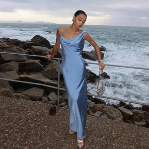 Robe longue en satin bleu clair élégante avec dos nu sur une plage pittoresque