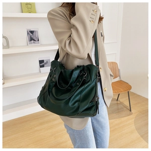 Model view showing the large dark green canvas tote bag and its draped shoulder fit