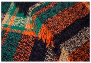 Detailed macro view of the checkered knit fabric texture and fringe on the plaid shawl
