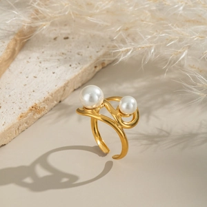 Elegant gold geometric ring with dual white pearls on a rustic stone background