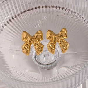 Detail of gold bow earrings featuring organic molten texture and high-polish finish