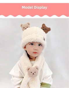 Detail of toddler cream plush knit hat and scarf set featuring cute teddy bear decor