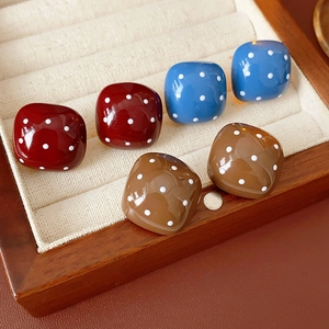 Quadratische Polka-Dot-Ohrringe in Rot, Blau und Braun in einer hölzernen Schmuckbox