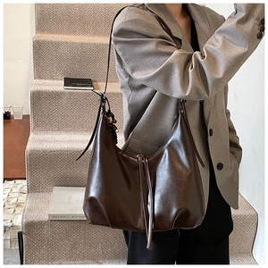 Detailed view of the large capacity dark brown leather hobo bag on a fashion model