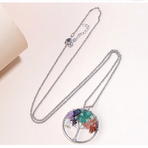 Close-up of silver tree of life pendant with multicolor crushed stone inlay on beige background