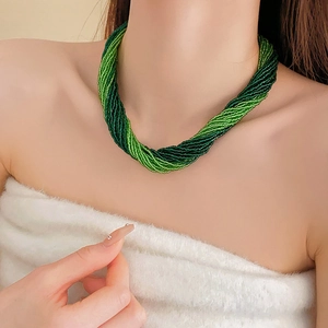 Detail of green beaded multilayer twisted necklace on model wearing white fuzzy top