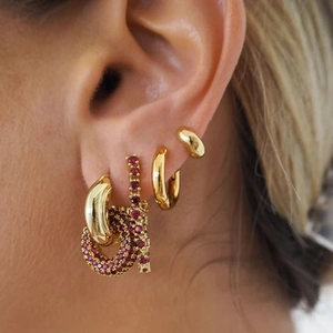Close-up of gold chain earrings with red pavé stones on model's ear