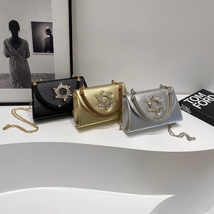 Elegant evening clutch bag set in black gold and silver with rhinestone sun motif