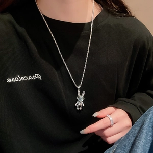 Detail of silver astronaut rabbit pendant necklace and pavé diamond ring worn by model
