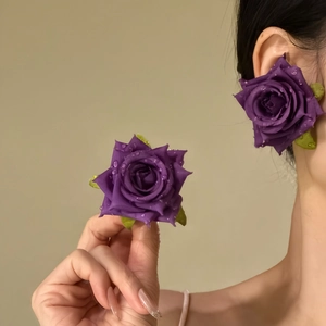Detailed close-up showing purple fabric rose earrings with realistic dewdrop petal details