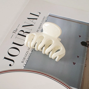 Detail shot of a minimalist cream white hair claw clip on a stylish lifestyle background