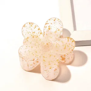 Detailed macro view of pink translucent flower hair claw with elegant gold fleck details