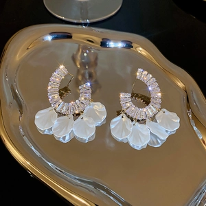 Dettaglio macro di orecchini a C in zircone di lusso con eleganti nappe a petalo bianco