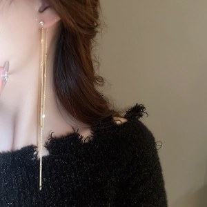 Close-up of elegant gold tassel earrings with zircon studs worn by a model