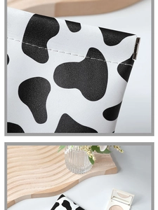 Close-up of cow print faux leather pouch showing detailed stitching and metal spring hinge
